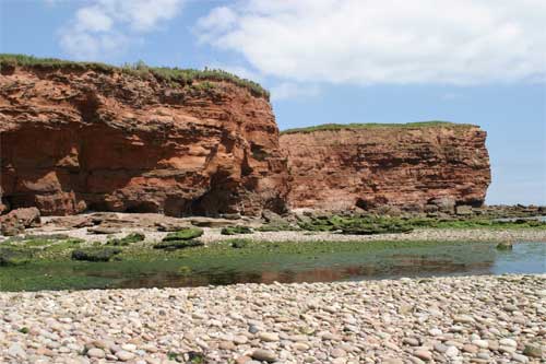 red cliffs and pebbles on the beach