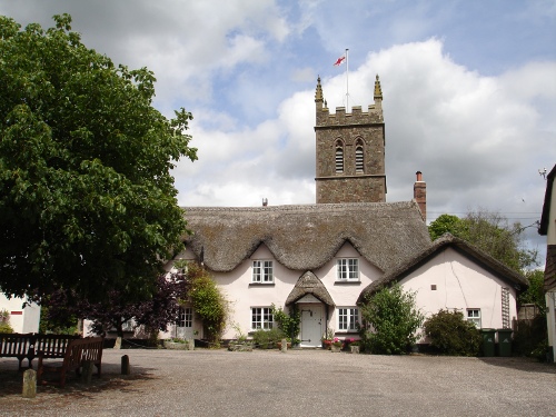 Sheepwash church tower behind thatched roofs